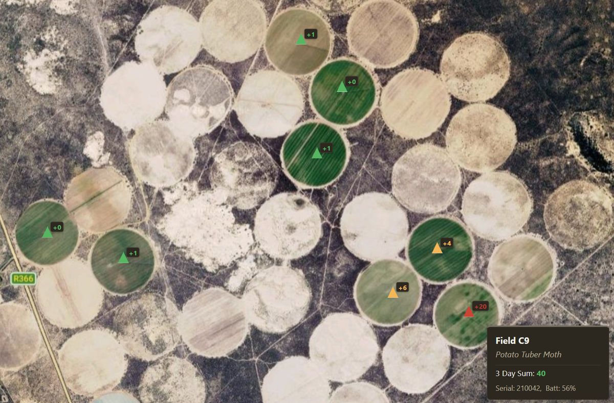 Satellite view of a farm with centre-pivot fields; each trap is a coloured triangle with the day's new catches, and a card shows the selected trap's block, three-day sum, serial and battery.